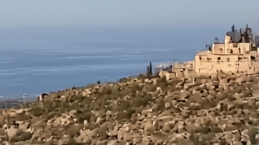 A hilltop fortress above southern Lebanon with distant military vehicles and smoke on the horizon