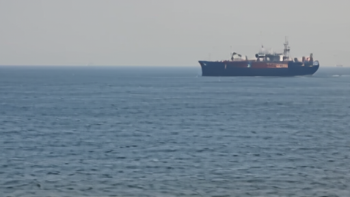 Red Sea shipping lane with a Houthi flag vessel in the distance, commercial ships turning back