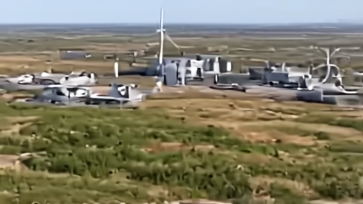Aerial of cleared farmland with surveyor stakes and a gas-turbine generation yard rising beside data-center shells