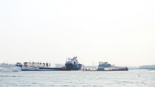 A bunkering vessel and fuel hoses at Fujairah with tankers waiting offshore under hazy Gulf light